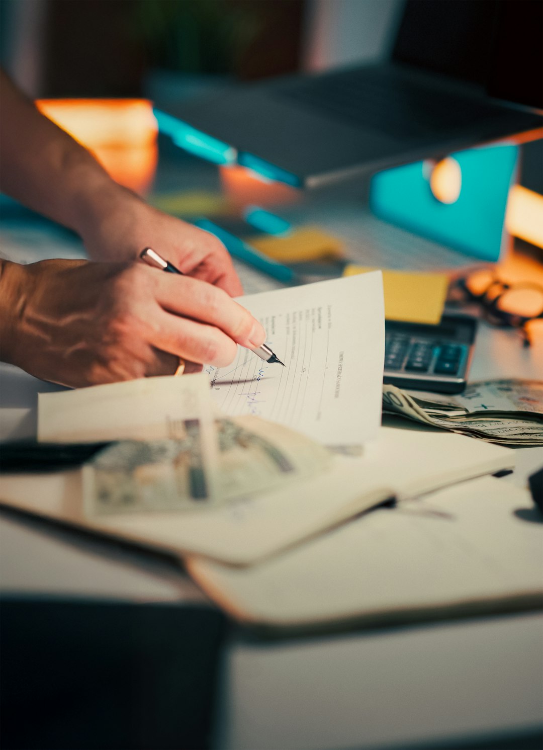 Hand signing document Polish zloty calculator finance Close-up of person filling out paperwork desk with cash calculator